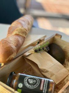 Das Bild beschreibt ein Gericht namens Floating Bowl für 2 Personen, das in einem Glas serviert wird und in nur 3 Minuten aufgewärmt werden kann. Es wird mit Baguette, Avocado und Kirschtomaten serviert und kostet 25,00 EUR